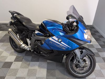 une moto bleue garée sur un sol à damier