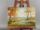 un chevalet sur lequel est posé un tableau représentant une rivière et des arbres