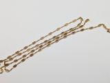 a close up of a gold necklace with a chain on a white surface