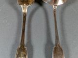 two spoons and a spoon rest on a table with a shadow