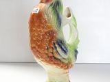 un vase orné d'un coq sur un fond blanc