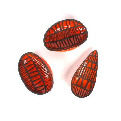 trois morceaux de verre rouge et noir posés sur une surface blanche