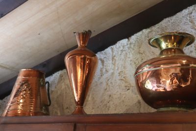 three copper vases sitting on a shelf in a room