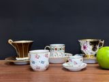 a green apple sitting on a table next to cups and saucers