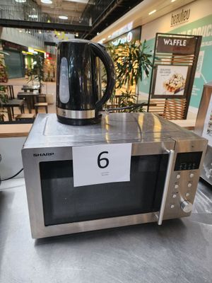 un micro-ondes argenté sur lequel est posé une bouilloire noire