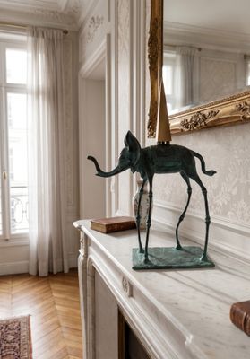 a statue of an elephant on a mantle in a room
