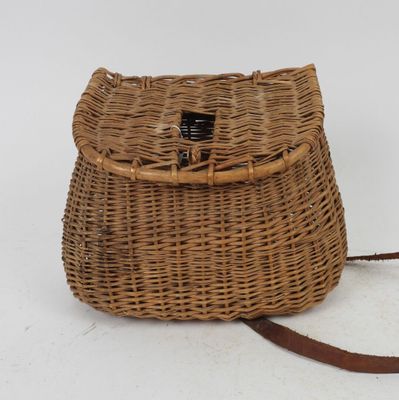 an old wicker purse with a leather strap on a white background