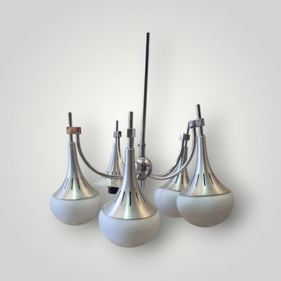 three white glass lamps hanging from a metal pole on a wall
