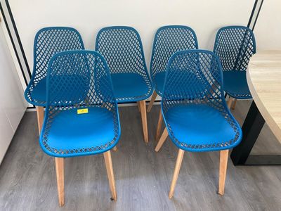 quatre chaises bleues placées les unes à côté des autres sur un plancher en bois