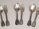four silver spoons and two forks are lined up on a white surface