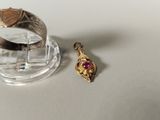 a gold ring with a red stone on it next to a silver ring
