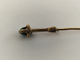 a close up of a gold stick with a green bead on it