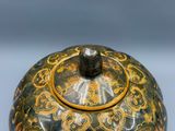 un vase vert et doré muni d'un couvercle, posé sur une table
