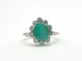 a close up of a ring with a green stone surrounded by diamonds