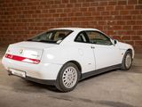 a white car that is parked in front of a brick wall