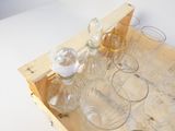 des bouteilles et des verres posés sur un plateau en bois, sur une table blanche