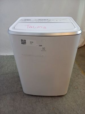 une machine à laver blanche posée par terre à côté d'un rideau