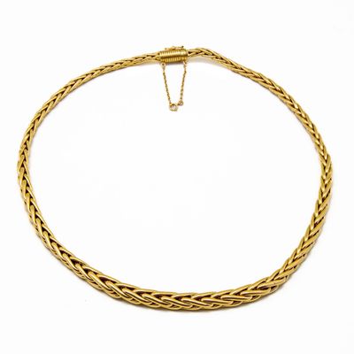 un collier en or avec un motif tressé sur fond blanc