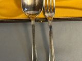 two silver spoons and a fork on a yellow napkin