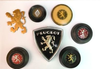 une photo montrant une collection d'emblèmes de voitures sur une surface blanche