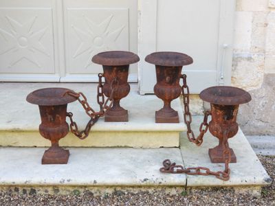 quatre urnes métalliques rouillées posées sur les marches d'une maison