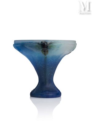 un bol en verre bleu avec un socle noir posé sur une surface blanche