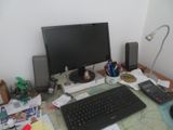 a desk with a computer, keyboard, mouse, and other items on it