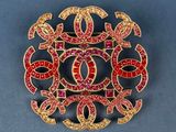 a close up of a brooch with red and yellow stones