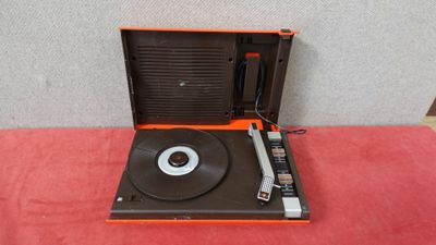 une platine vinyle orange et noire posée sur une table rouge