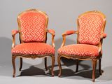 paire de fauteuils en bois sculpté de style Louis XV, recouverts de tissu rouge