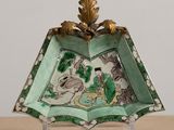 a green and white plate with a gold leaf decoration on it