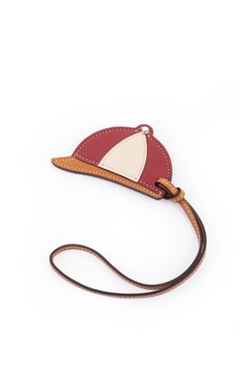 Le petit sac rouge et blanc est muni d'une bandoulière marron et orné d'une voile blanche.