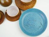 a blue plate with a design on it next to a bowl and two cups