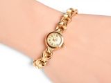 an image of a woman ' s wrist with a gold watch on it