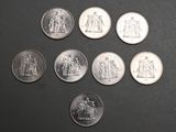 six different types of silver coins on a black surface