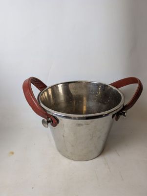 a metal bucket with a leather handle on a table
