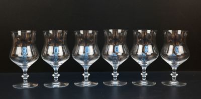 six empty wine glasses lined up on a table