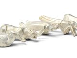 three silver figurines of animals on a white surface