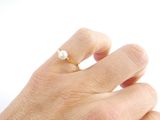 a person ' s hand with a pearl ring on it