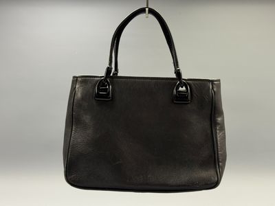 black leather tote bag hanging from a hook on a wall