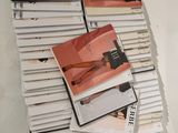 a pile of magazines on a table with a woman ' s legs on them