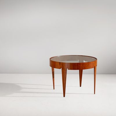 une table ronde avec un plateau en verre, posée sur un meuble blanc