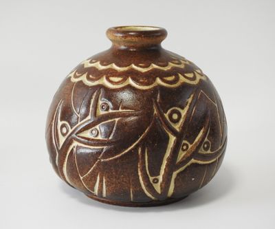 un vase brun orné d'un motif sur une surface blanche
