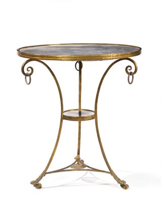 une table en laiton avec un plateau en verre et un piètement en métal
