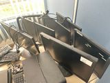 a lot of computer monitors and keyboards on the desk