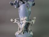 a blue vase with a statue and flowers in it
