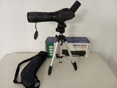 un télescope noir posé sur un trépied, à côté d'un sac noir