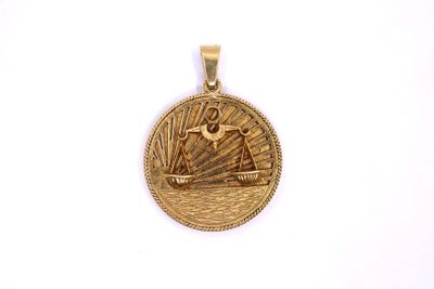 a close up of a gold pendant with a ship on it