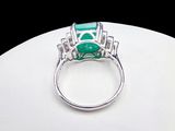 an image of a ring with a green stone surrounded by diamonds