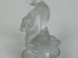 a glass figurine of a boy sitting on a rock